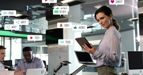 Businesswoman leading digital marketing meeting with tablet and social media alerts