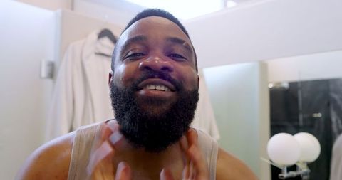 Man caring for beard in modern bathroom with lights