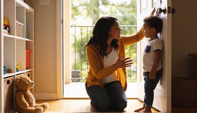 Kneeling caregiver measuring toddler height at doorway, bonding milestone moment