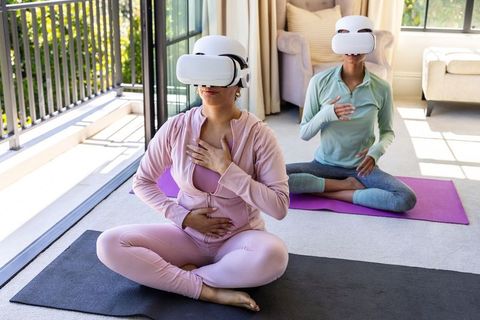 Diverse women practicing vr breathwork and mindful yoga in sunlit living room