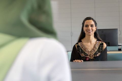 Indian receptionist smiling and welcoming client at modern office front desk