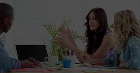Woman leading team discussion and brainstorming around laptop in bright modern office
