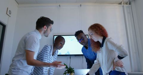 Diverse Team Collaborating Over Laptop in Casual Workspace