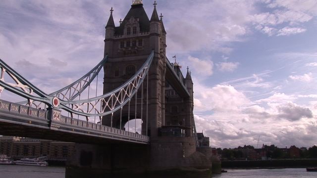 Tower Bridge in London spans river Thames with overcast sky and detailed architecture on display. Useful for travel blogs, London attraction guides, architectural features, or backgrounds conveying a mood of historic European aesthetics. Highlights themes of iconic landmarks and travel destinations.