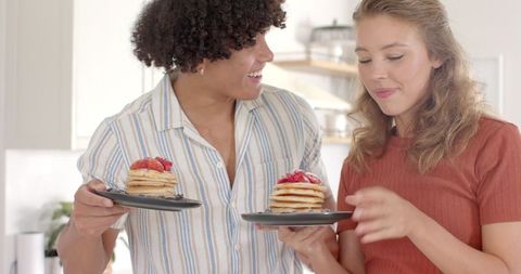 Diverse couple enjoying pancake breakfast in modern kitchen