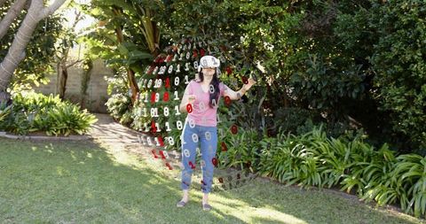 Woman wearing vr headset interacting with floating binary sphere in sunny backyard