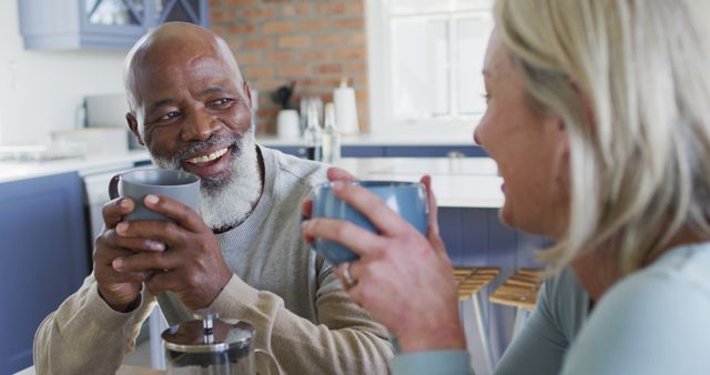 Biracial senior couple holding coffee cups smiling looking at each other at home - Download Free Stock Photos Pikwizard.com