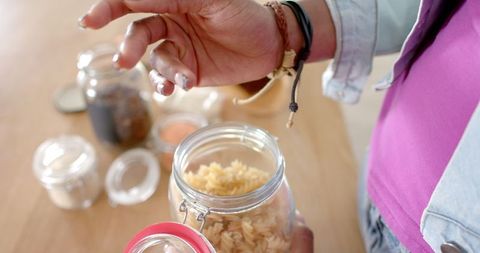 Woman Opening Jar of Pasta in Bright Kitchen