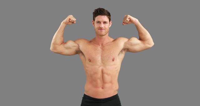 A young Caucasian man showcases his muscular physique by flexing his biceps, with copy space. His confident expression and strong build emphasize a focus on fitness and strength.