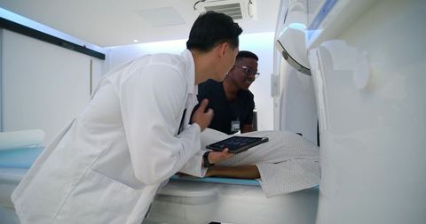 Medical team positioning patient for ct scan using tablet in radiology suite