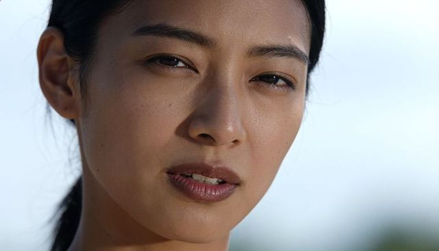 Serene asian woman holding steady gaze closeup freckled skin natural light portrait