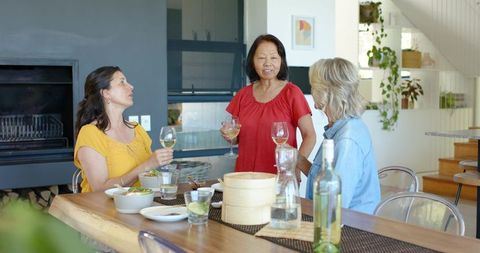 Diverse women sharing casual lunch and wine around sunlit modern dining table