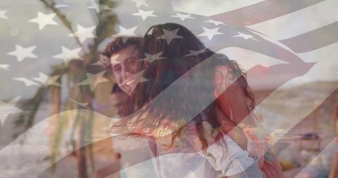 Smiling couple riding piggyback along sunlit beach with american flag double exposure