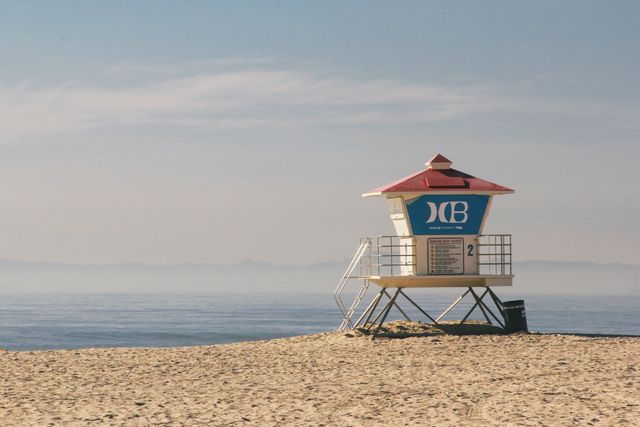 Lifeguard tower overlooking serene sandy beach with calm ocean backdrop. Useful for travel brochures, tourism websites, coastal safety campaigns, and relaxation-themed images conveying tranquility and beach safety.