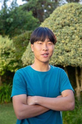 Smiling Asian Man in Relaxed Pose in Lush Garden