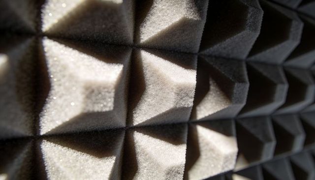 Close-up pyramidal acoustic foam panels casting dramatic shadows and sparkling texture
