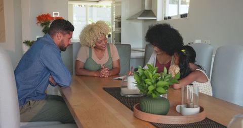 Family gathering around dining table discussing together