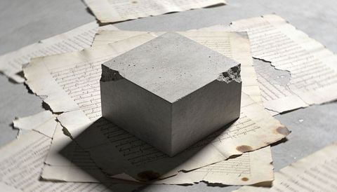 Concrete Cube Casting Angular Shadow on Weathered Cursive Manuscripts