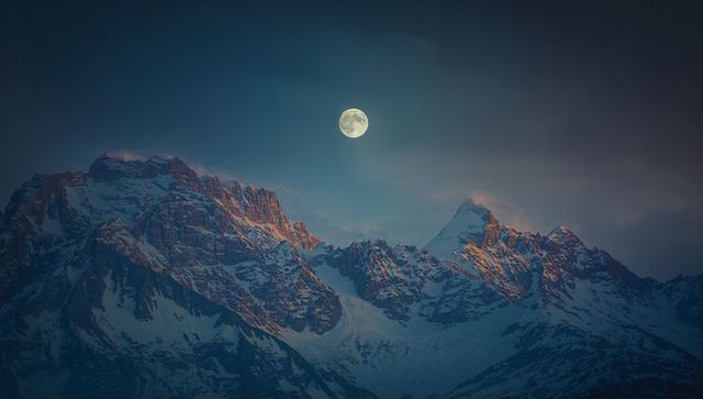 Full Moonlit Dusk Over Snow-Capped Mountain Peaks