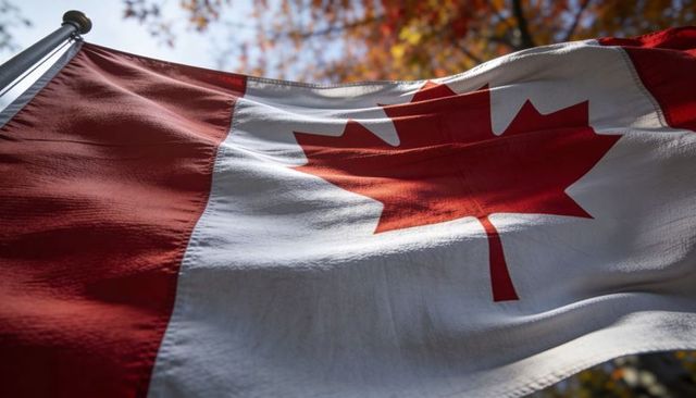 Waving canadian flag under autumn trees with red maple leaf closeup and fabric texture