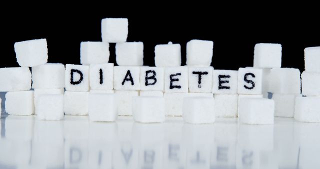 Sugar cubes are arranged to spell out 'DIABETES' against a black background, with copy space. It symbolizes the connection between sugar consumption and the risk of developing diabetes.