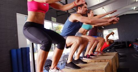 Group performing plyo box squats at gym during functional training class