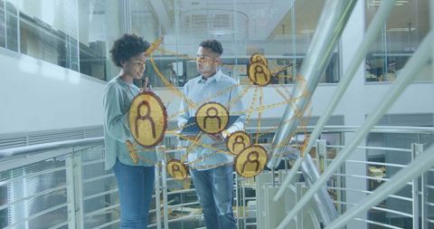 Colleagues collaborating on tablet in modern office atrium with digital network overlay