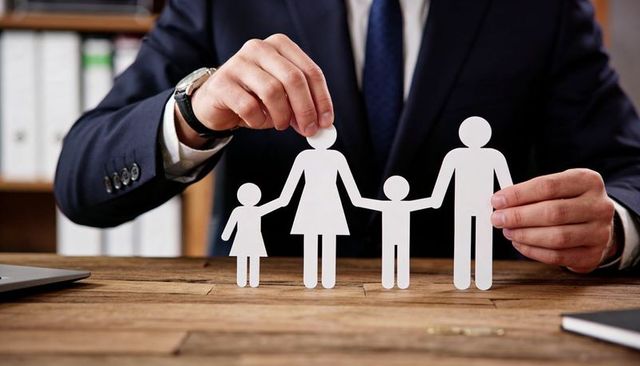 Businessman placing paper family cutouts on desk for insurance protection concept