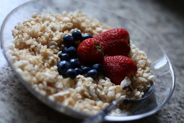 Appealing depiction of a nutritious breakfast with whole grain cereal garnished with fresh strawberries and blueberries. Ideal for illustrating healthy eating habits, diet plans, or breakfast menus. Perfect for use in nutrition blogs, diet and health articles, meal planning guides, or advertisements promoting healthy eating.