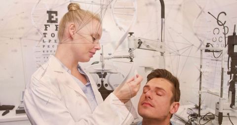 Optometrist administering eye drops to patient in exam room