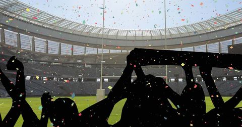 Silhouetted fans cheering in stadium with colorful confetti falling