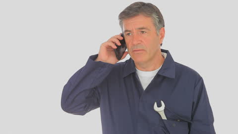 Mechanic in Uniform Answering Call with Mobile Phone