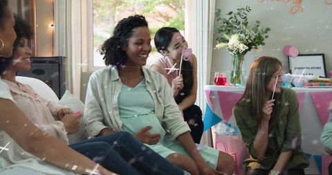 Friends celebrating mother-to-be with pastel decorations and gifts at baby shower