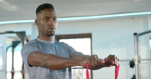 African american man training with red resistance band in gym for focused strength workout
