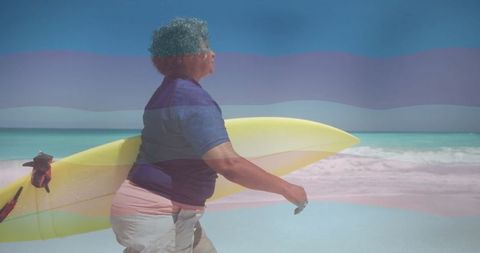 Senior woman carrying surfboard along beach shoreline