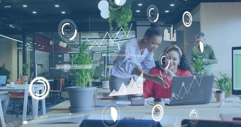 Collaborating team analyzing data on laptop with HUD analytics overlay in modern office