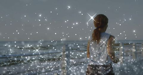 Woman Standing by Seafront Railing Facing Ocean Featuring Sparkling Star Bokeh Overlay