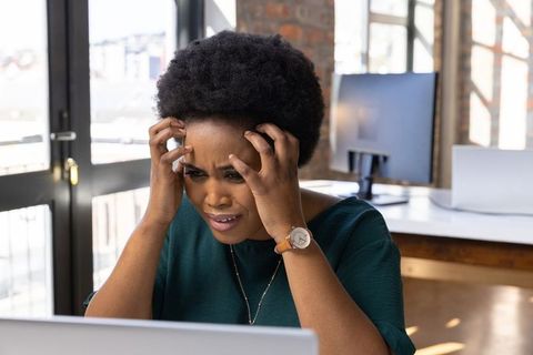 Stressed Woman Working on Laptop in Modern Office Environment