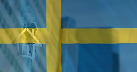 Silver house key with swedish flag in background symbolizing home ownership