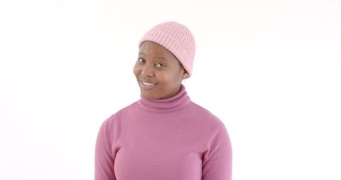 Smiling woman in pink beanie and sweater exuding confidence