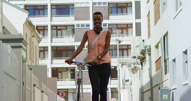 Young woman happily walking with bicycle down a narrow city alley. Ideal for urban lifestyle concepts, transportation, fitness, and casual city life usage.