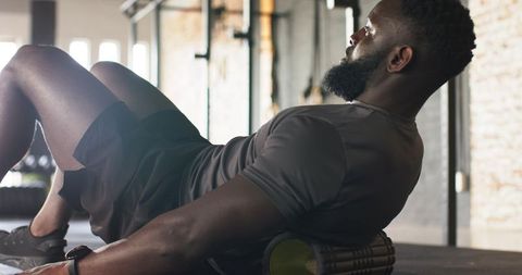 Athlete using foam roller for muscle recovery in gym
