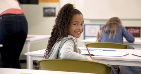 Smiling African American Girl in Modern Classroom, Learning and Writing