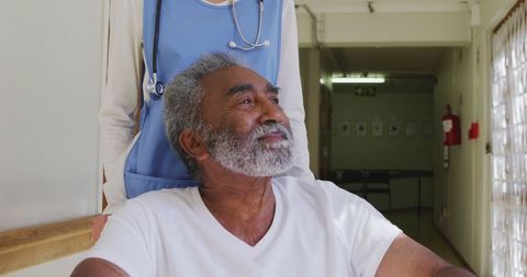 Senior Man in Wheelchair with Doctor in Retirement Home Corridor