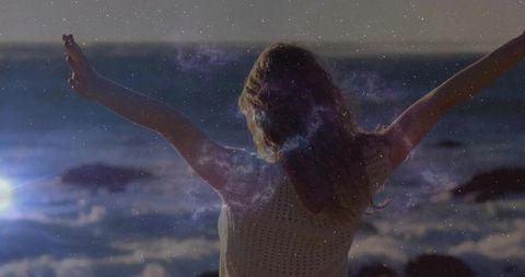 Ethereal woman embracing freedom by sea at sunset