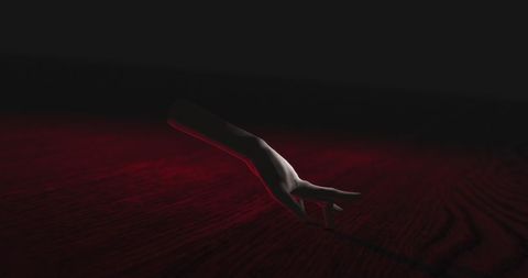 Creepy hand walking in shadows with red glow