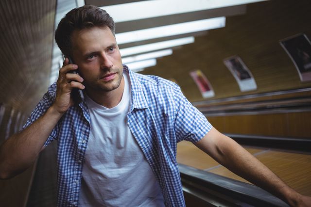 Handsome man talking on mobile phone on escalator - Download Free Stock Photos Pikwizard.com