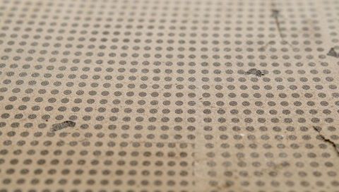Vintage dotted cardboard texture with creases tears and scuffs closeup macro surface