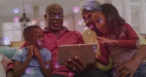 Multigenerational family connecting on tablet on sofa, grandparents teaching grandchildren