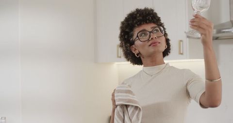 Woman polishing wine glass during kitchen preparation